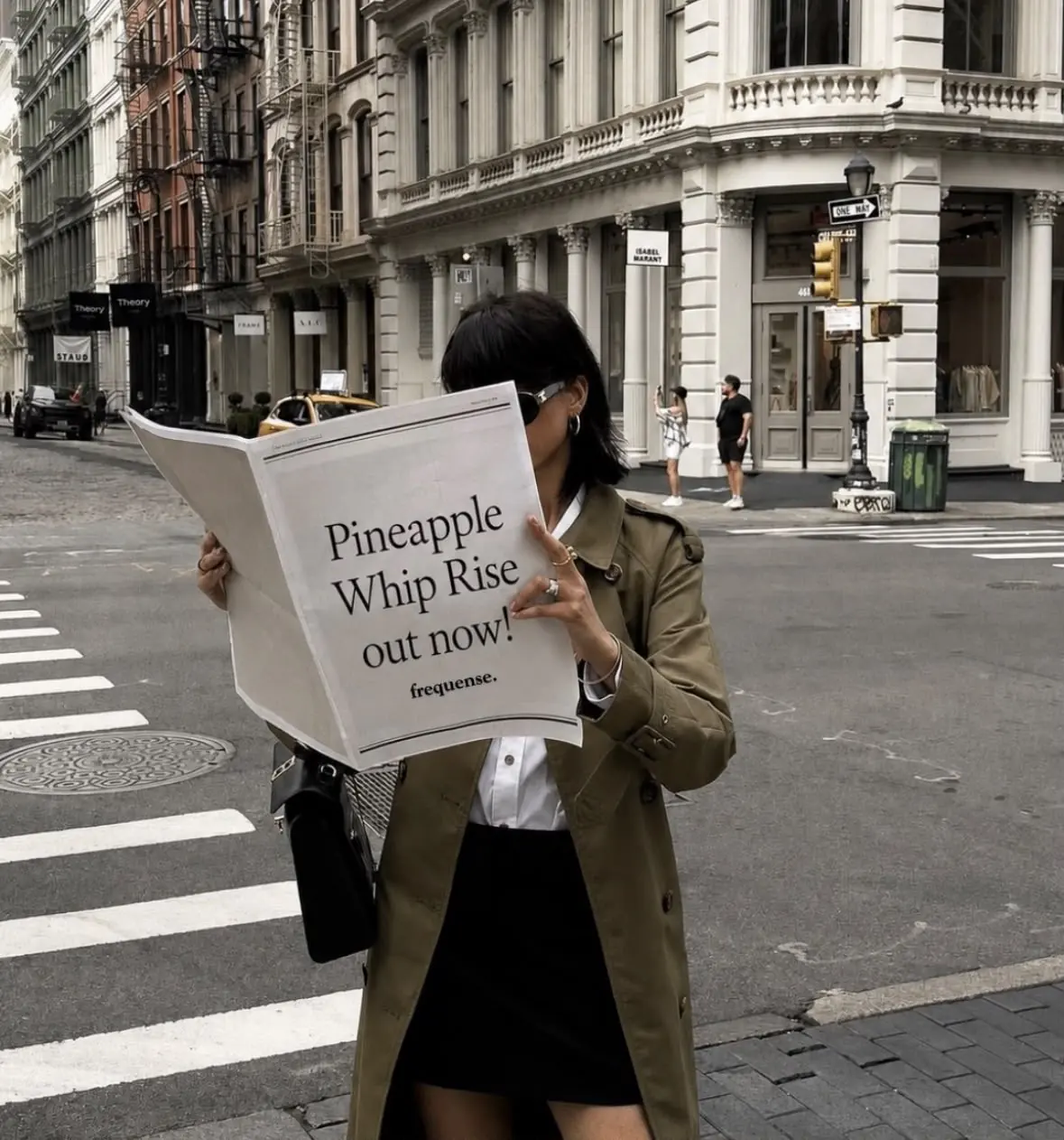 A woman on a city street reading a newspaper carrying a frequense announcement.